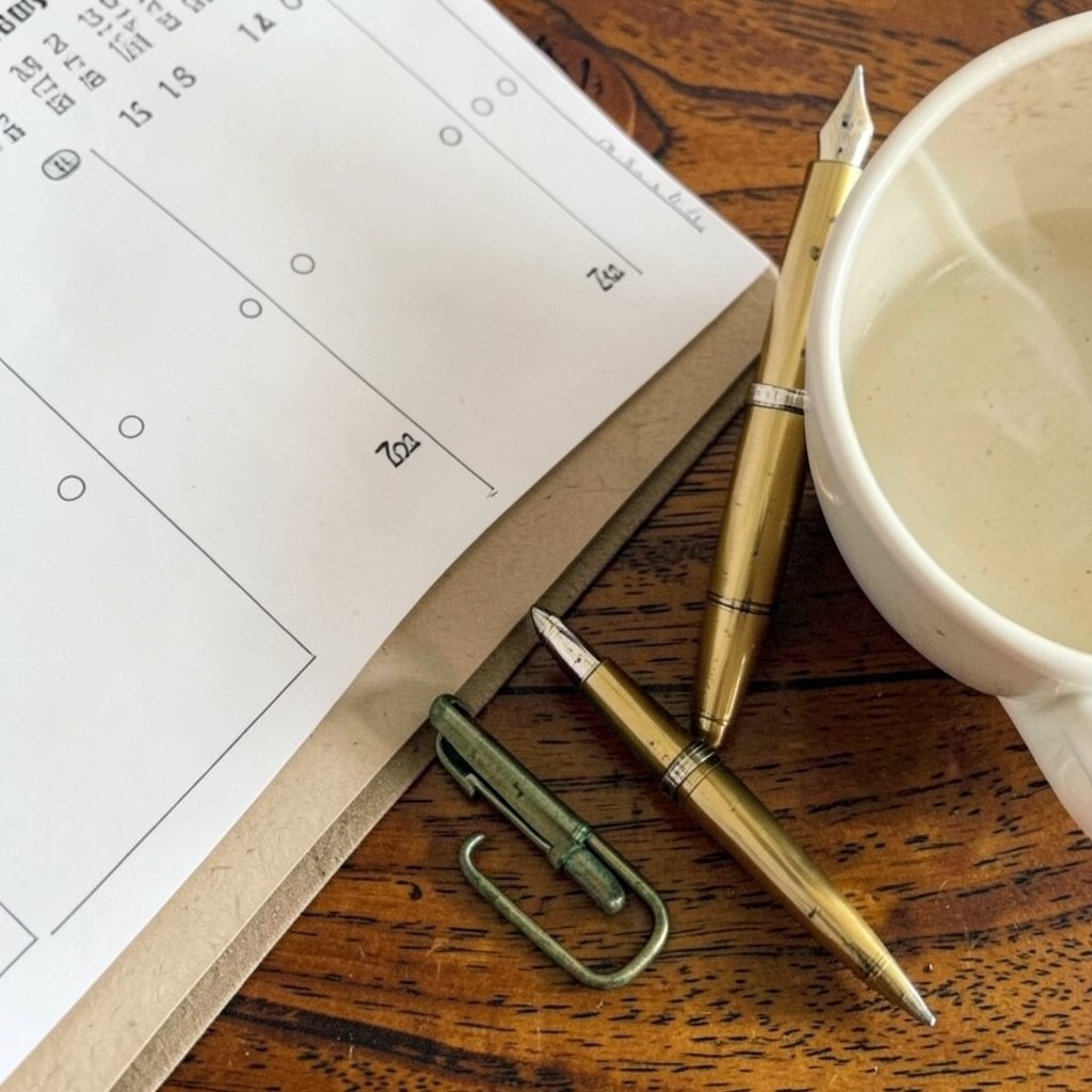 Calendrier papier marquant les dates de congé maternité avec stylo et tasse de thé sur un bureau